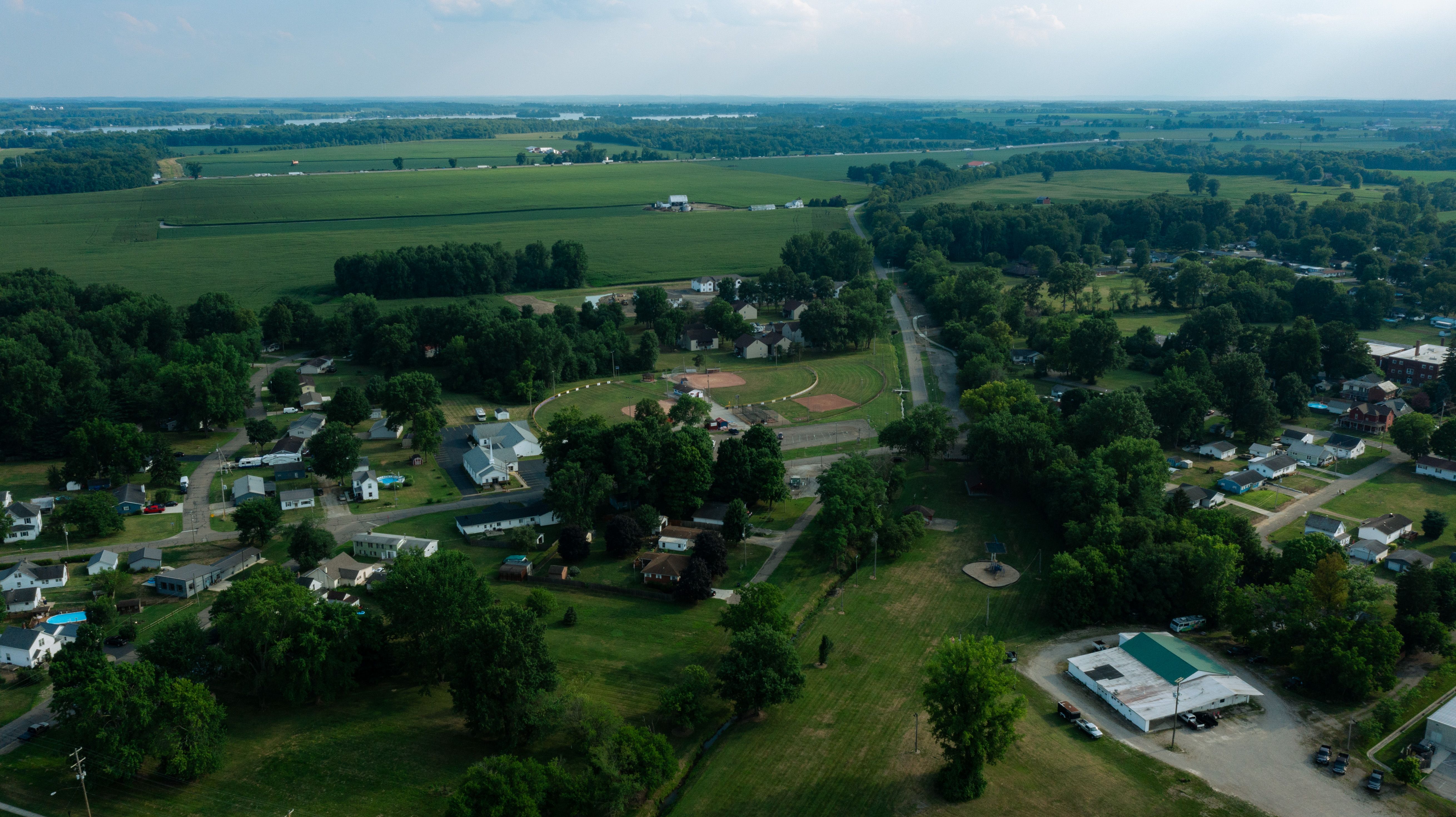 Aerial view of a rural landscape with green fields, scattered homes, and winding roads.