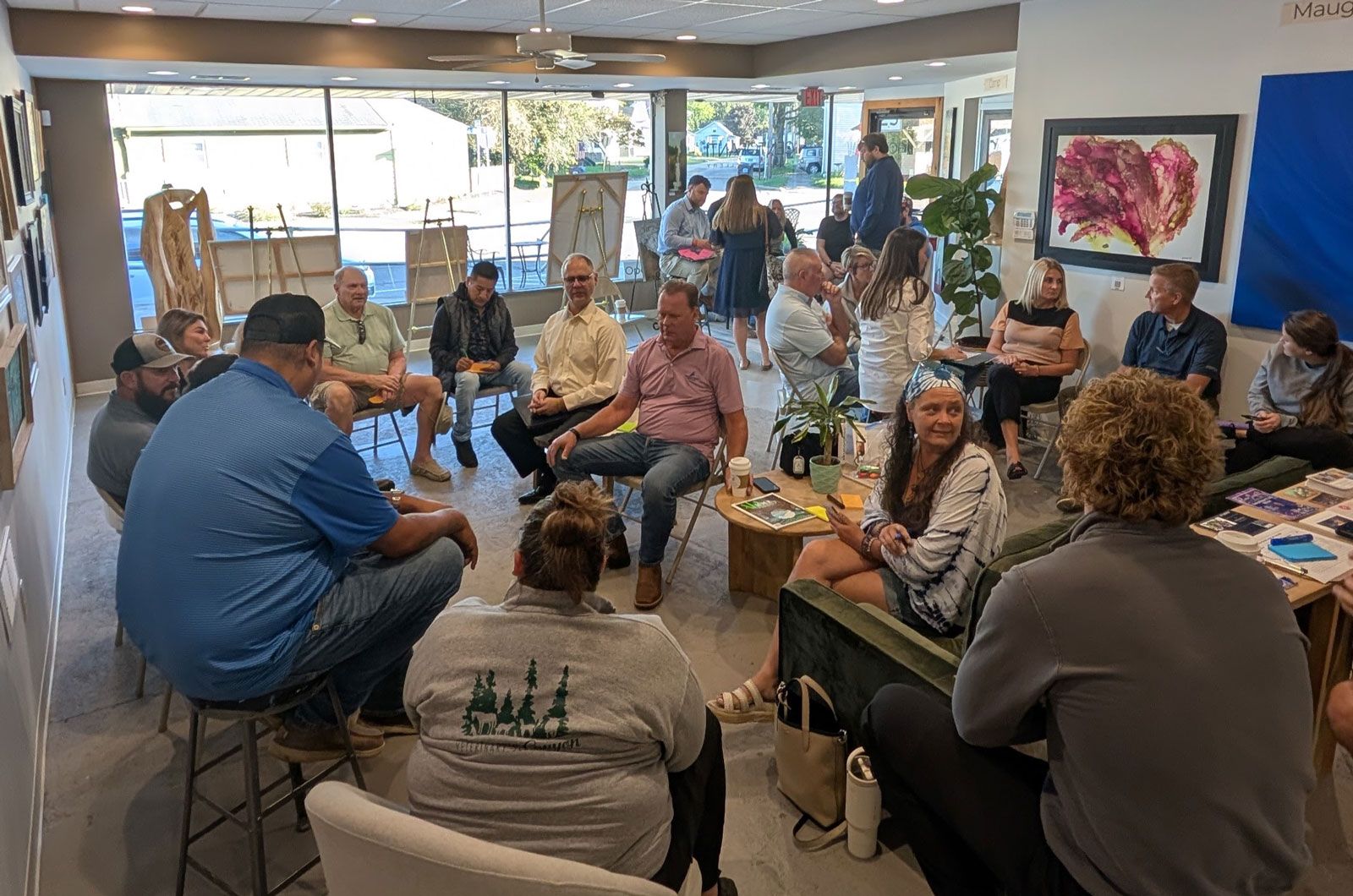 A diverse group of people casually gathered in a bright room, conversing and interacting.